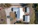 Aerial view of the light green house with white metal roof and detached sheds, surrounded by trees and water at 1493 New Point Comfort Rd, Englewood, FL 34223