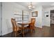 Cozy dining area with a round wood table set under an elegant light fixture and a view of the bathroom at 1493 New Point Comfort Rd, Englewood, FL 34223