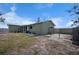 Exterior view of the light green house with the chain link fenced backyard and a detached shed at 1493 New Point Comfort Rd, Englewood, FL 34223