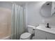 Bathroom featuring a shower with curtain, toilet, and modern sink with a round mirror at 1495 New Point Comfort Rd, Englewood, FL 34223