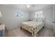 Bright bedroom with a white frame bed, seashell bedding, tile flooring, and a side table at 1495 New Point Comfort Rd, Englewood, FL 34223