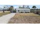 Charming single-story home with white exterior, carport, tidy landscaping, and a large front yard at 1495 New Point Comfort Rd, Englewood, FL 34223