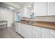 Spacious kitchen featuring stainless steel sink, white cabinets, and tile floors at 1495 New Point Comfort Rd, Englewood, FL 34223