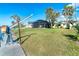 Waterfront backyard with a boat lift, screened-in patio, and green grass under a clear blue sky at 275 North Dr, Englewood, FL 34223