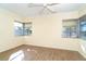 Bright bedroom featuring wood-look floors, a ceiling fan, and two windows for natural light at 275 North Dr, Englewood, FL 34223