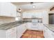 Bright kitchen features terracotta tile, stone countertops, and stainless steel appliances with white cabinets at 275 North Dr, Englewood, FL 34223