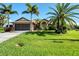 Single-story home with a two-car garage, palm trees, and well-manicured lawn at 39 Tournament Rd, Rotonda West, FL 33947