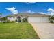 Single-story home with three-car garage, landscaped lawn, and paver driveway at 5 Broadmoor Ln, Rotonda West, FL 33947