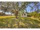 View of the backyard with a storage shed and mature trees at 6125 Higgins Ln, Englewood, FL 34224