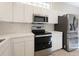 Kitchen with stainless steel appliances and white cabinetry at 6730 Greenview Ln, Englewood, FL 34224