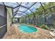 A view of the enclosed pool with landscaped perimeter and outdoor dining furniture at 8389 Hebron Rd, Port Charlotte, FL 33981