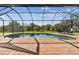 Inviting screened-in pool area with brick pavers, seating, and a view of lush greenery at 9533 Arnaz Cir, Port Charlotte, FL 33981