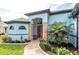 Inviting front entrance features a red door with stone accents, complemented by lush landscaping and a winding brick pathway at 9548 Applin Cir, Port Charlotte, FL 33981