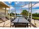 Outdoor dining table and chairs on patio with views of the lake and lush foliage through the screen at 1112 Andrews St, Englewood, FL 34224