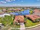 Stunning aerial view of the home with a well-manicured lawn, lake views, and tile roof at 13347 Golf Pointe Dr, Port Charlotte, FL 33953