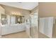 Bright bathroom featuring double sinks, a large mirror, a walk-in shower, and a separate soaking tub at 13347 Golf Pointe Dr, Port Charlotte, FL 33953