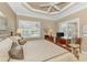 Serene bedroom featuring a comfortable bed, tray ceiling, and bright natural light from plantation-shuttered windows at 13347 Golf Pointe Dr, Port Charlotte, FL 33953