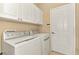 Efficient laundry room with a side-by-side washer and dryer and overhead storage cabinets at 13347 Golf Pointe Dr, Port Charlotte, FL 33953