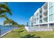 Stunning waterfront condo building with balconies, a pool, and lush palm trees along the shoreline at 1375 Beach Rd # 109, Englewood, FL 34223