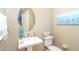 Cozy powder room featuring a pedestal sink, round mirror, and coastal-themed decor at 1375 Beach Rd # 109, Englewood, FL 34223