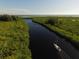 Aerial view of a sailboat cruising down a waterway with lush green banks at 13951 Allamanda Cir, Port Charlotte, FL 33981