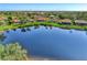 A picturesque aerial view of a lake reflecting the sky surrounded by well-maintained homes and lush landscaping at 14405 Silver Lakes Cir, Port Charlotte, FL 33953