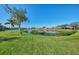 Lush green backyard and lake with mature shade trees and palm trees under a blue sky at 14405 Silver Lakes Cir, Port Charlotte, FL 33953