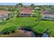 Aerial shot of a backyard with a screened in patio, lush green grass, mature trees, and serene lake views at 14405 Silver Lakes Cir, Port Charlotte, FL 33953