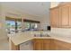 Well-lit kitchen with wooden cabinets, stainless steel dishwasher, double sink and view of the outside patio at 14405 Silver Lakes Cir, Port Charlotte, FL 33953