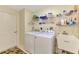 Well-lit laundry room features front load washer and dryer with utility sink and wire rack shelving at 14405 Silver Lakes Cir, Port Charlotte, FL 33953