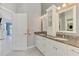 Bathroom featuring granite countertops, dual sinks, and a large mirror with decorative lighting at 14429 Bridgeview Ln, Port Charlotte, FL 33953