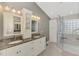 Bathroom featuring dual sinks with granite countertops, a glass-enclosed shower, and neutral tile flooring at 14429 Bridgeview Ln, Port Charlotte, FL 33953