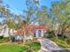 Charming one-story home with a red tile roof, arched entry, and mature trees in a manicured lawn at 14429 Bridgeview Ln, Port Charlotte, FL 33953