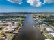 Aerial view of waterfront homes situated along a canal, surrounded by lush vegetation and clear skies at 15524 Ruston Cir, Port Charlotte, FL 33981