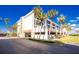 Exterior view of condo building with covered parking, blue sky and palm trees at 1591 Beach Rd # 403, Englewood, FL 34223