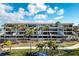 Exterior view of the condo complex featuring palm trees and well-manicured landscaping at 1591 Beach Rd # 403, Englewood, FL 34223