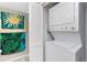 Compact laundry closet featuring a stacked washer and dryer unit and convenient storage space at 1651 Beach Rd # 301, Englewood, FL 34223