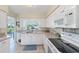 Well-lit kitchen featuring white cabinets, modern appliances, and a window overlooking the backyard at 1710 Loralin Dr, Englewood, FL 34223