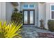 Charming entrance with a stone walkway leading to a double-door entryway and lush tropical landscaping at 18502 Arapahoe Cir, Port Charlotte, FL 33948