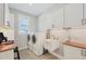 Well-lit laundry room featuring white cabinets, a sink, and updated appliances at 18502 Arapahoe Cir, Port Charlotte, FL 33948