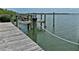 Dock view over the water, showcasing sturdy wooden supports, mooring post and tropical foliage at 2255 N Beach Rd # 12, Englewood, FL 34223