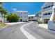 Exterior shot of white condos and driveway lined with palm trees under a clear blue sky at 2255 N Beach Rd # 12, Englewood, FL 34223