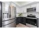 Modern kitchen with stainless steel refrigerator, oven, microwave, and stylish white and dark cabinets at 2255 N Beach Rd # 12, Englewood, FL 34223