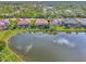 Waterfront home with a tile roof, lush landscaping, and a serene lake view surrounded by mature trees at 2660 Sable Palm Way, Port Charlotte, FL 33953