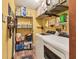 Yellow laundry room featuring a washer/dryer, shelving with cleaning supplies and wood-look tile floors at 3204 Depew Ave, Port Charlotte, FL 33952