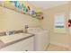 Bright laundry room featuring a utility sink, washer, dryer, window, and convenient shelving at 43 Blue Hen Dr, Placida, FL 33946