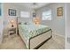 Bright bedroom with light tile flooring, a comfortable queen bed with decorative green pattern comforter and two windows at 5031 Lucine Rd, Venice, FL 34293