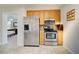 A kitchen with stainless steel refrigerator and oven, and light wood colored cabinets, plus an adjacent bedroom at 5031 Lucine Rd, Venice, FL 34293