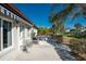 Backyard featuring a concrete patio, tropical landscaping, and a blue-striped awning at 525 Foxwood Blvd, Englewood, FL 34223