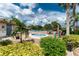 Community pool area featuring a spa, seating, and lush landscaping under a sunny sky with palm trees at 525 Foxwood Blvd, Englewood, FL 34223